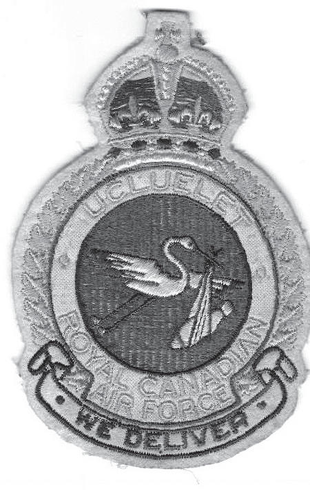 An embroidered badge with a stork flying through the air carrying a cloth in its beak. Above the stork is a crown. The text on the badge reads the following: Ucluelet Royal Canadian Air Force, We Deliver