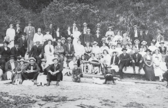 A group of about 50 people sitting and standing on logs while posed for the camera. 