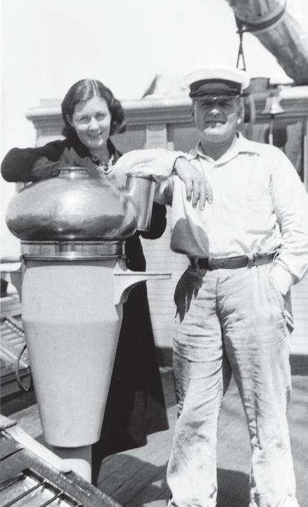 A man and a woman stand on a boat while smiling at the camera. 