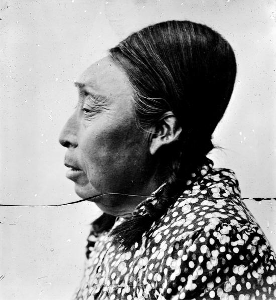 Profile photograph of a Kwakiutl woman her hair fastened in braids.