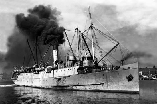Photograph of Princess Maquinna during WW II painted in camouflage paint, dark smoke coming out of the funnel. Dark clouds fill the sky.