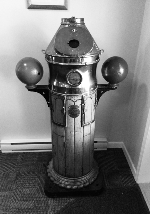 Photograph of the binnacle in a corner on a carpeted floor.