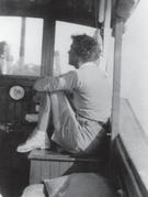 Capi sitting with her arms wrapped aroun her knees on the Caprice, facing away from the camera