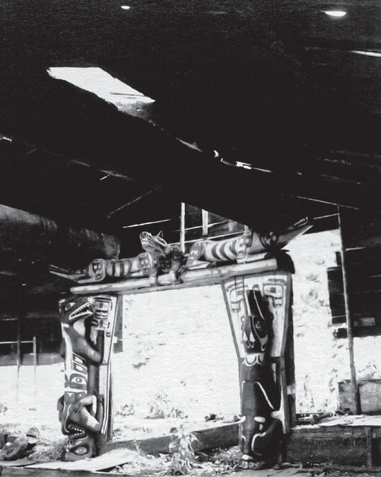 The interior of an Indigenous big house with two totems of wolflike creatures by the entrance