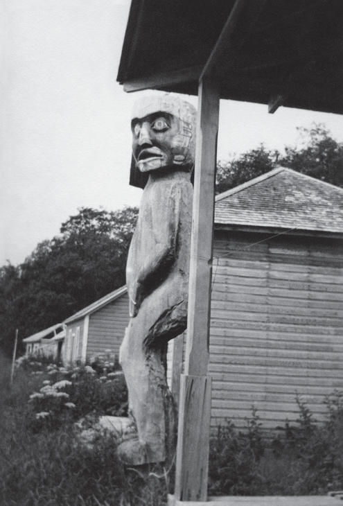 A large sculpure of a person amidst wooden houses