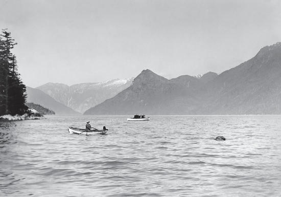 A view from shore of ocean and mountains with two small rowboats in the water