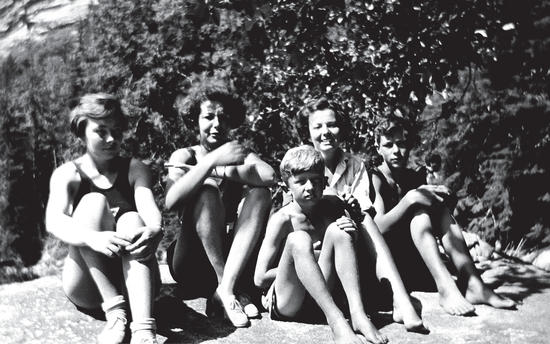 A photo of Capi's children, now as young adults and teenagers, all sitting on a rock in the sun