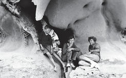 Two young boys and Capi exploring sandstone caves