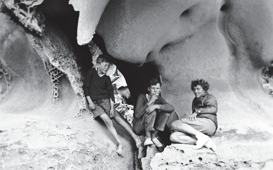 Two young boys and Capi exploring sandstone caves