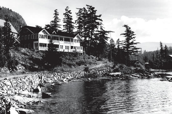 A large building standing on the edge of the water, surrounded by trees