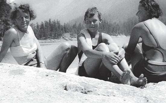 Capi and two of the children in their bathing suits, sitting on a rock