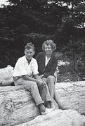 Capi sitting on a log with one of her teenaged sons