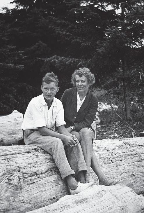 Capi sitting on a log with one of her teenaged sons