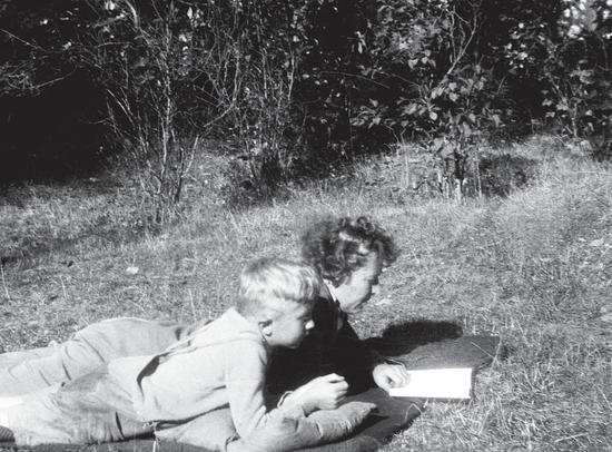 Capi and one of her children lying alongside each other on their stomachs, looking at a book