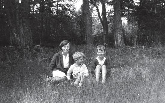 Three of the children sitting in a meadow together, facing the camera