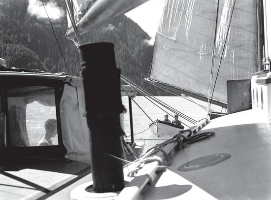 The Caprice attached to a sailboat with two little boys in a rowoat behind