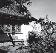 api as an older woman in her rocking chair in her garden, facing away from the camera