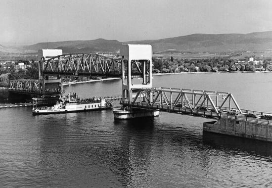 A section of a bridge being raised as a boat passes underneath.
