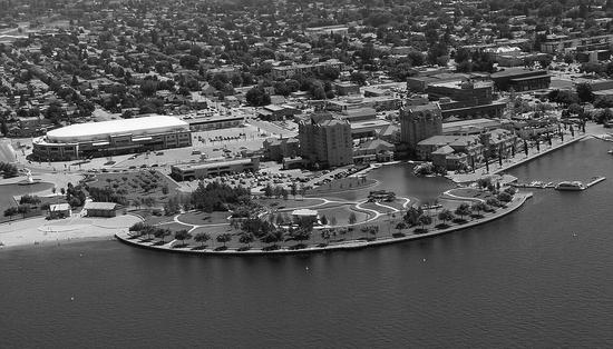 An aerial view of a waterpark by a body of water. Behind it is a city.