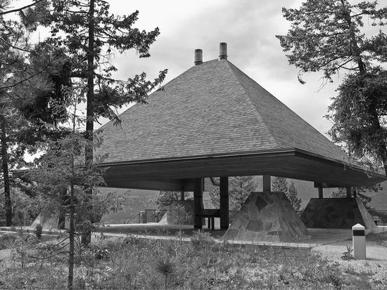 An outdoor roofed area surrounded by trees.