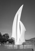 A large white statue consisting of three pointed protrusions, curved to emulate sails.