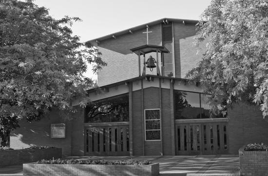 A light-coloured church with a spire surrounded by trees with no leaves.