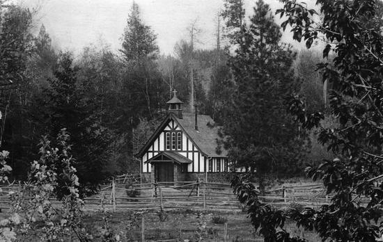 A small building surrounded by trees. Around the building are fences made of sticks.