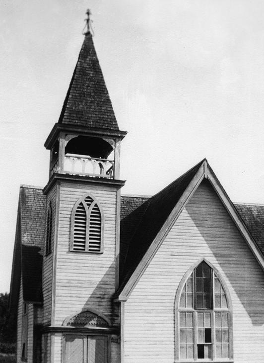 A light-coloured wooden church with a spire.