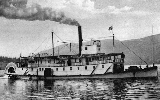 A steam boat on a body of water. A cloud of steam billows from it.