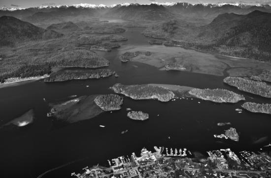 Clayoquot Sound has hundreds of small islands made of ancient volcanic rock. Thousands of years of erosion by glaciers and wave action shaped these islands. The mud flats, home to thousands of birds and a wealth of marine life, can be seen to the right. Tofino appears at the bottom of the photo, and Opitsat on the left, on Meares Island, across the harbour.