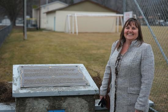 Andrea Malysh stands beside the memorial plaque on the site of the Vernon Internment Camp.
